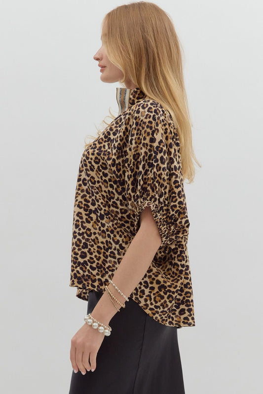 Leopard print high neck elasticated sleeve band dolman top featuring accented multicolor rib band split neck. Unlined. Woven. Non-sheer. Lightweight